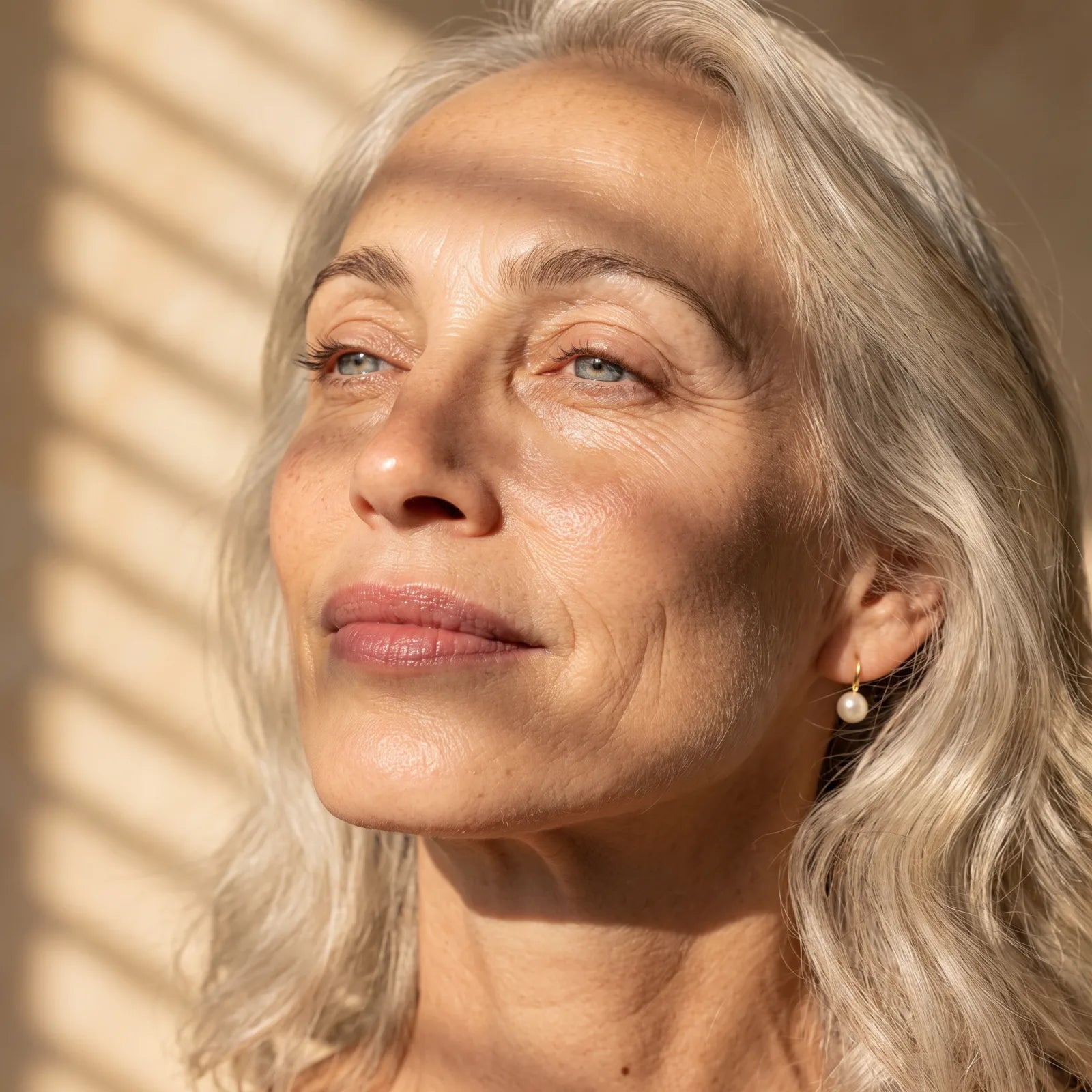 Woman in her late 50s with healthy, natural skin by a window